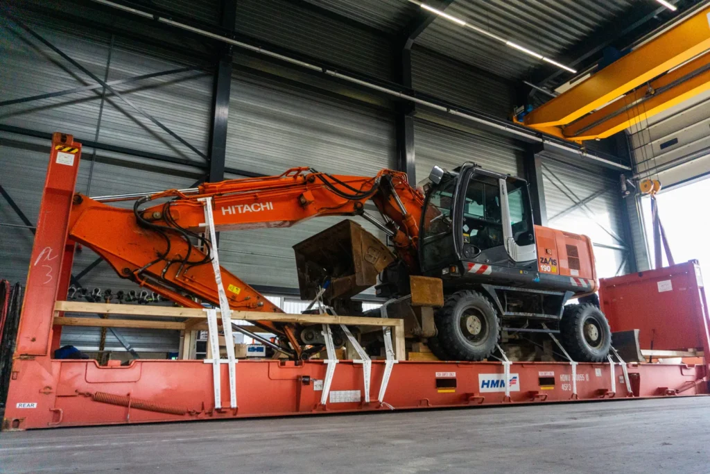 Gesjorde en gezekerde graafmachine op een flatrack