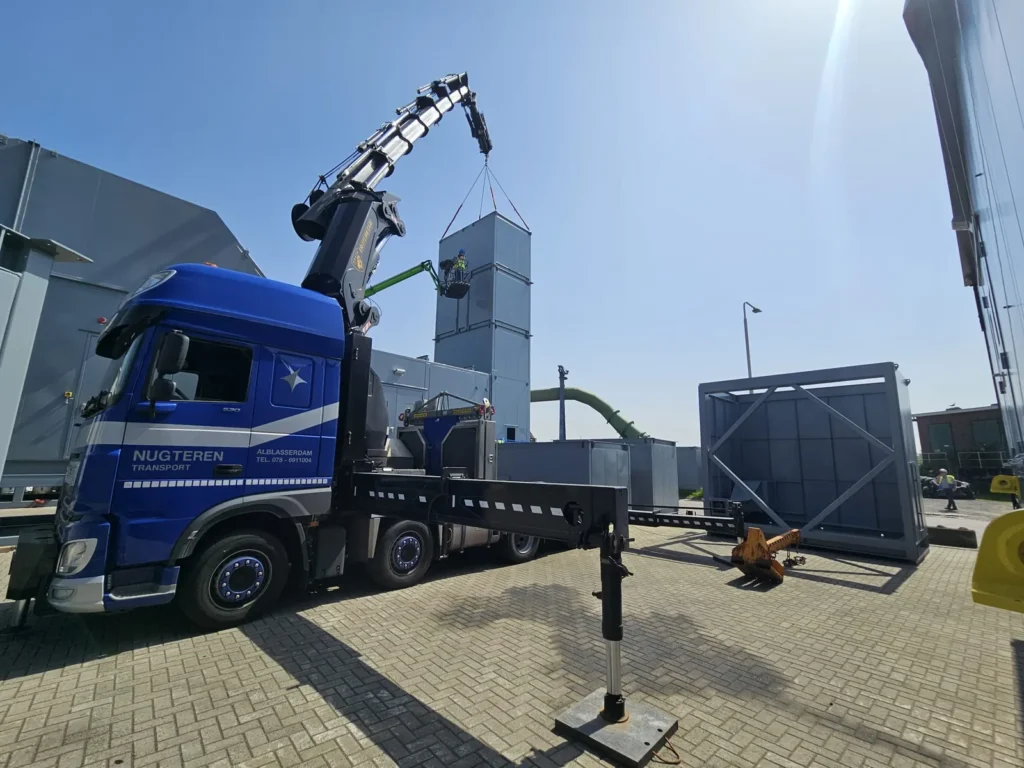 Kraanwagen van Nugteren Transport hijst een luchtbehandelingskast op een industrieterrein