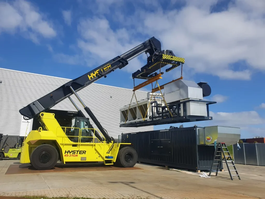 Reachstacker hijst een luchtbehandelingsunit op het buitenterrein